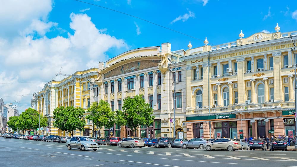 A street with parked cars and a building with a sign that says "ОБИРКА".