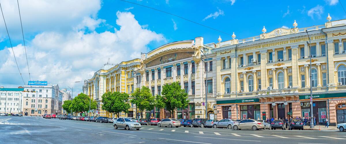 A street with parked cars and a building with a sign that says "ОБИРКА".
