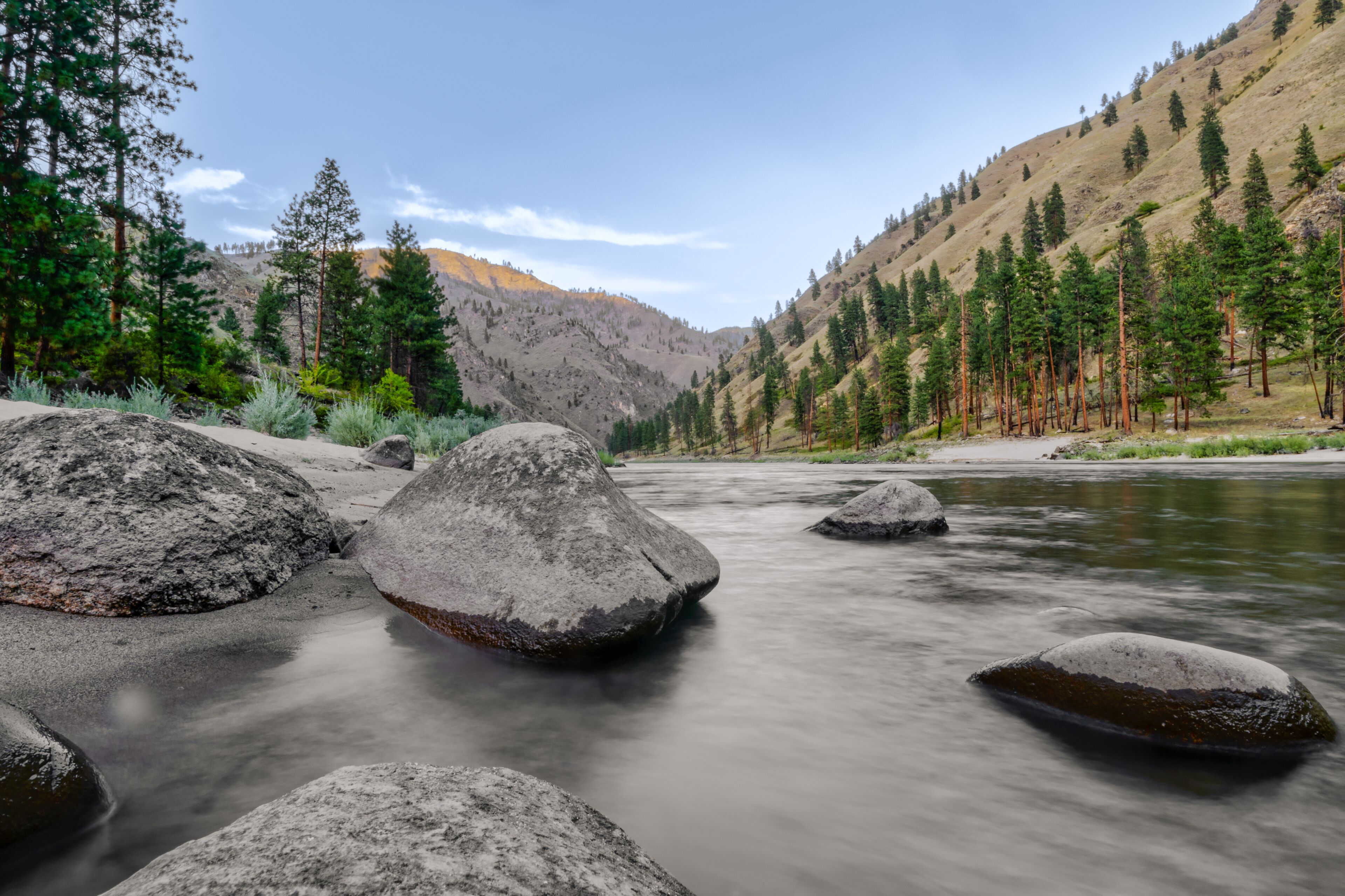 Wide angle long exposure view of little Salmon river on rocky beach with mountain views in Riggins Idaho