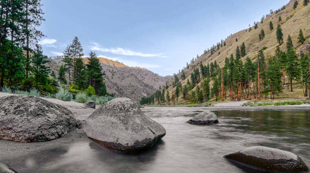 Wide angle long exposure view of little Salmon river on rocky beach with mountain views in Riggins Idaho