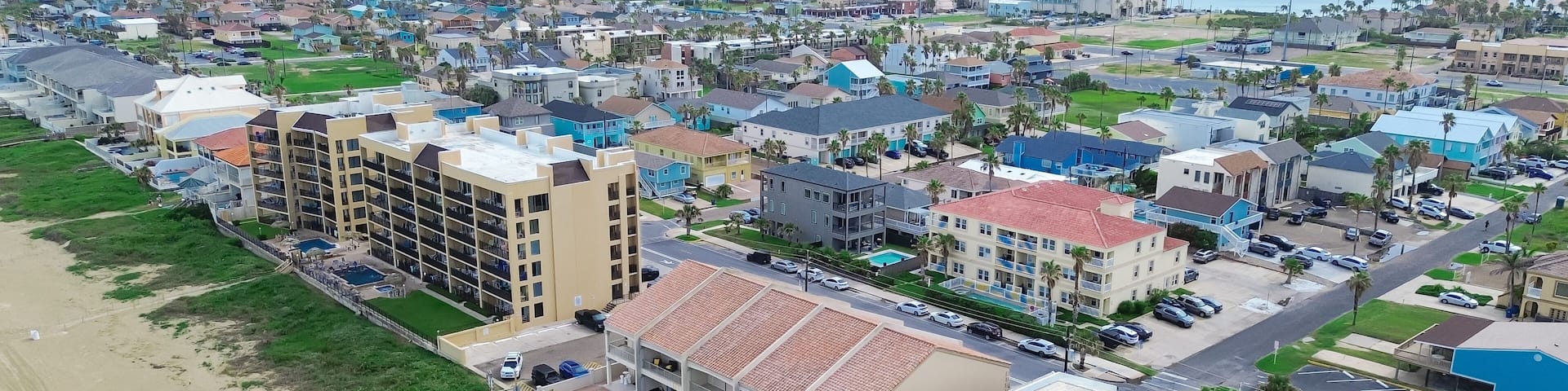 Beach condos, hotel with swimming pool, boardwalk access to sandy shoreline tropical South Beach, South Padre Island, exquisite barrier Gulf Coast of Texas, people enjoy beach activities aerial