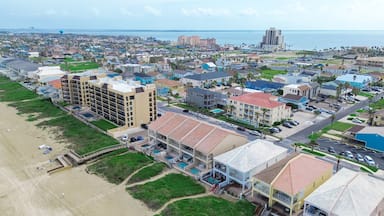 Beach condos, hotel with swimming pool, boardwalk access to sandy shoreline tropical South Beach, South Padre Island, exquisite barrier Gulf Coast of Texas, people enjoy beach activities aerial