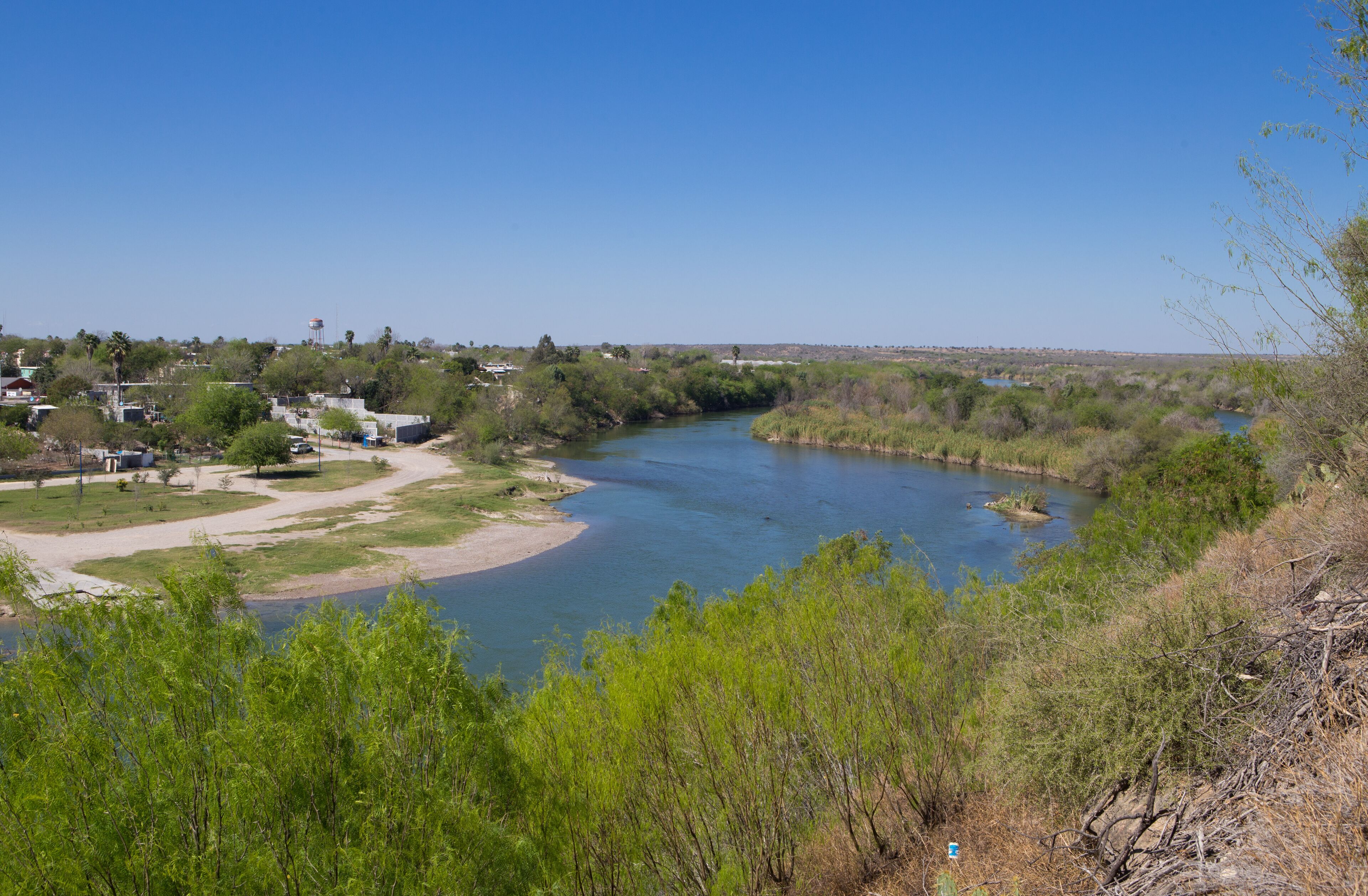 A river winding through a green landscape with buildings and trees.