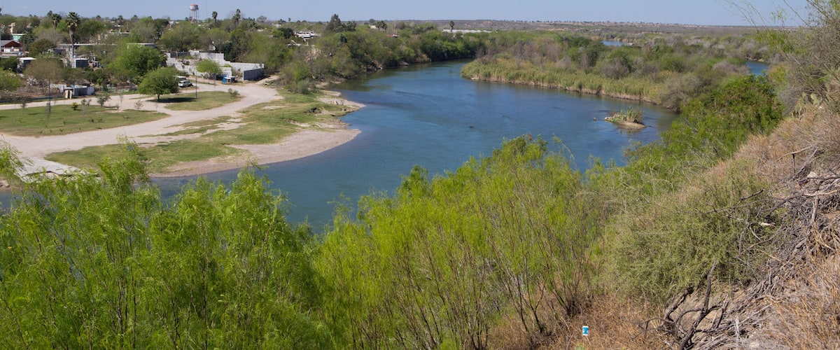 A river winding through a green landscape with buildings and trees.
