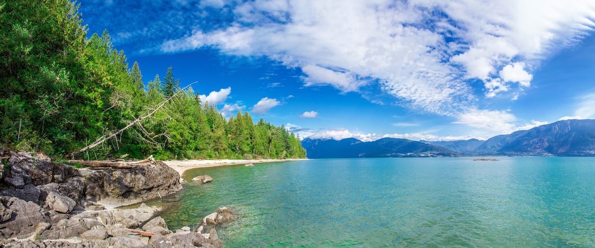 A clear lake surrounded by mountains and dense forest.