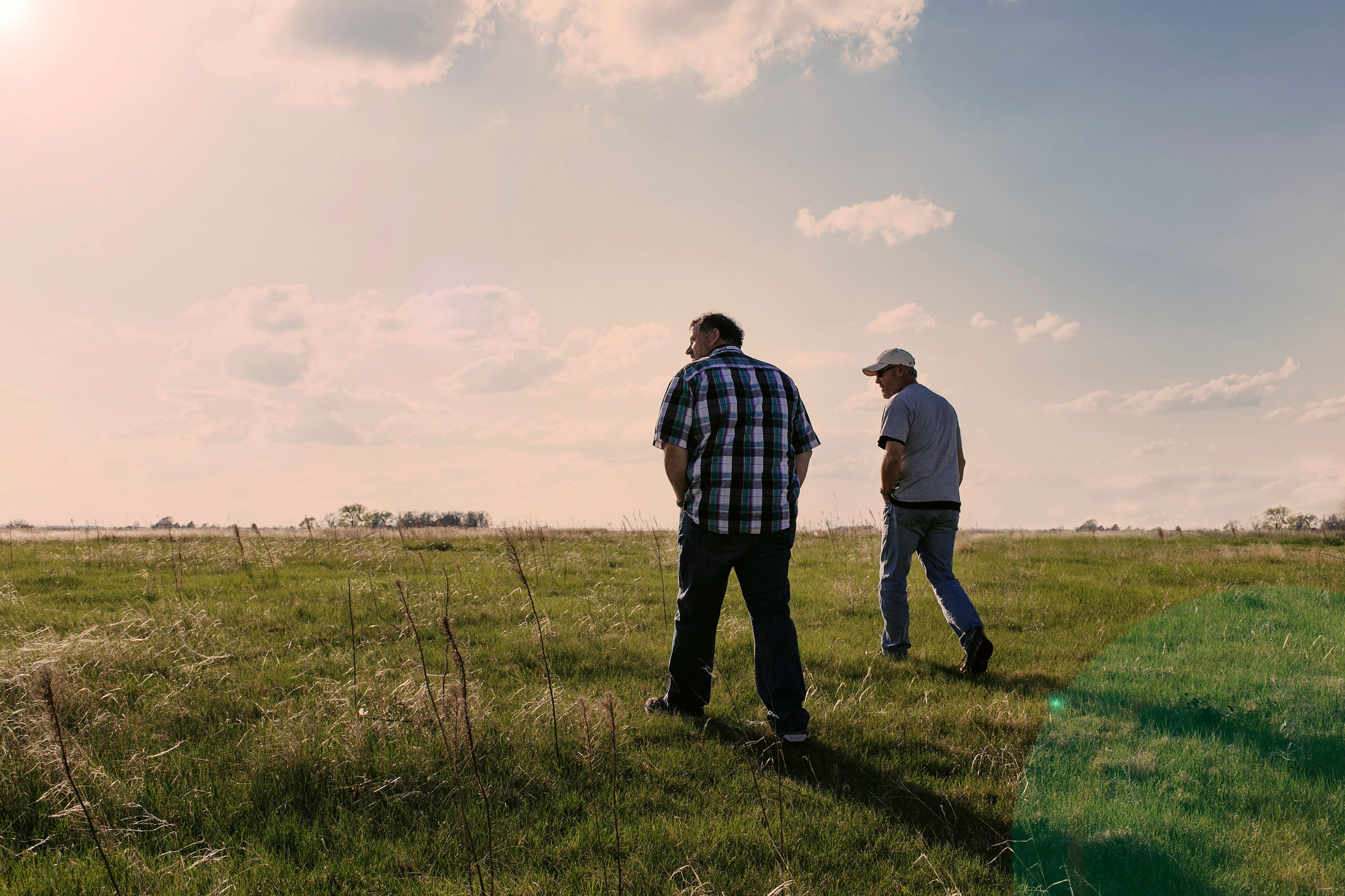 Two mature men walking in field landscape near Hastings Nebraska, USA