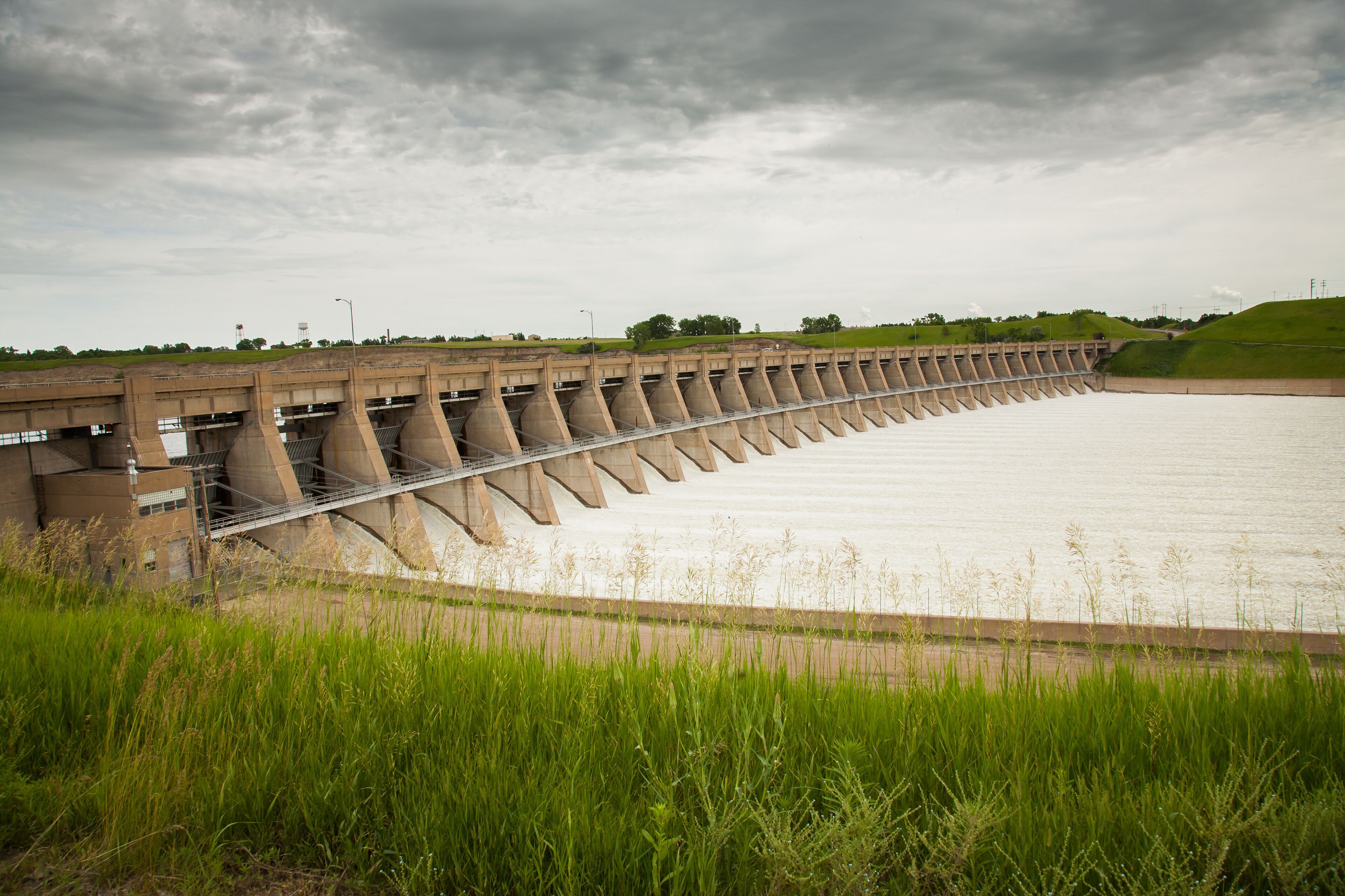 A large dam with multiple spillways and a grassy foreground.