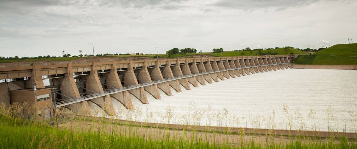 A large dam with multiple spillways and a grassy foreground.