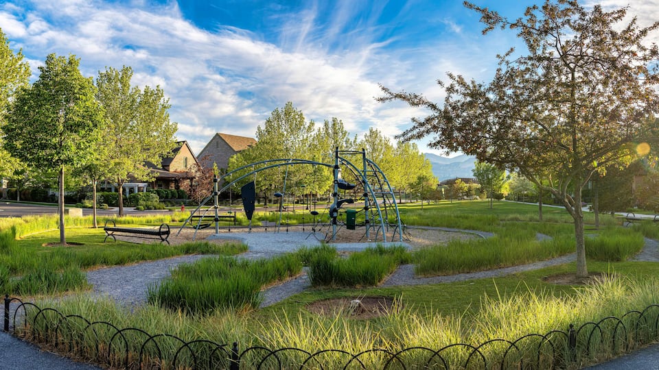 A park with a playground, walking paths, and surrounding trees.