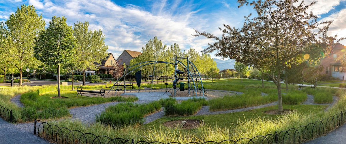A park with a playground, walking paths, and surrounding trees.