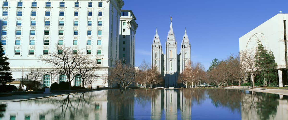 A cityscape with a large cathedral, a modern building, and a reflective water body.