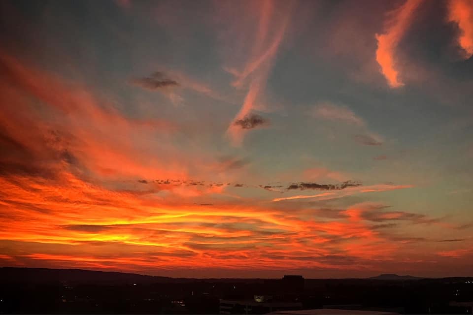 A sunset with vibrant orange and red clouds over a cityscape.