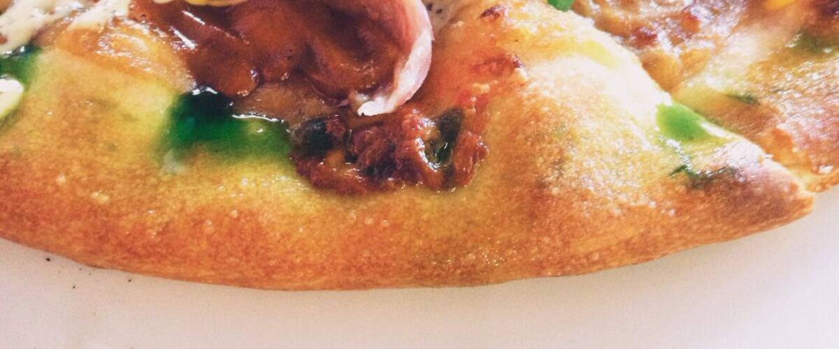 A pizza topped with various meats, cheese, and green onions.