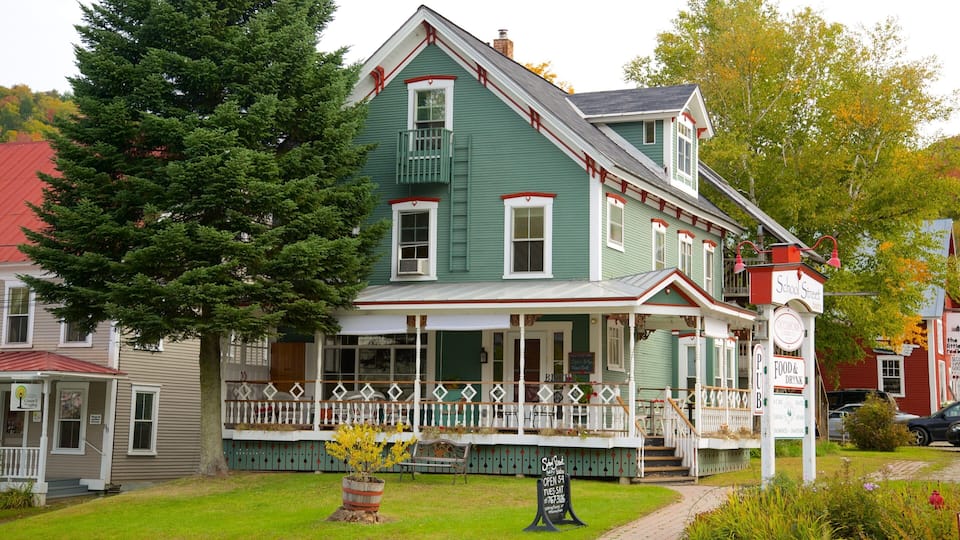 A green Victorian-style house with a porch, a red car parked in front, and a tree to the left.