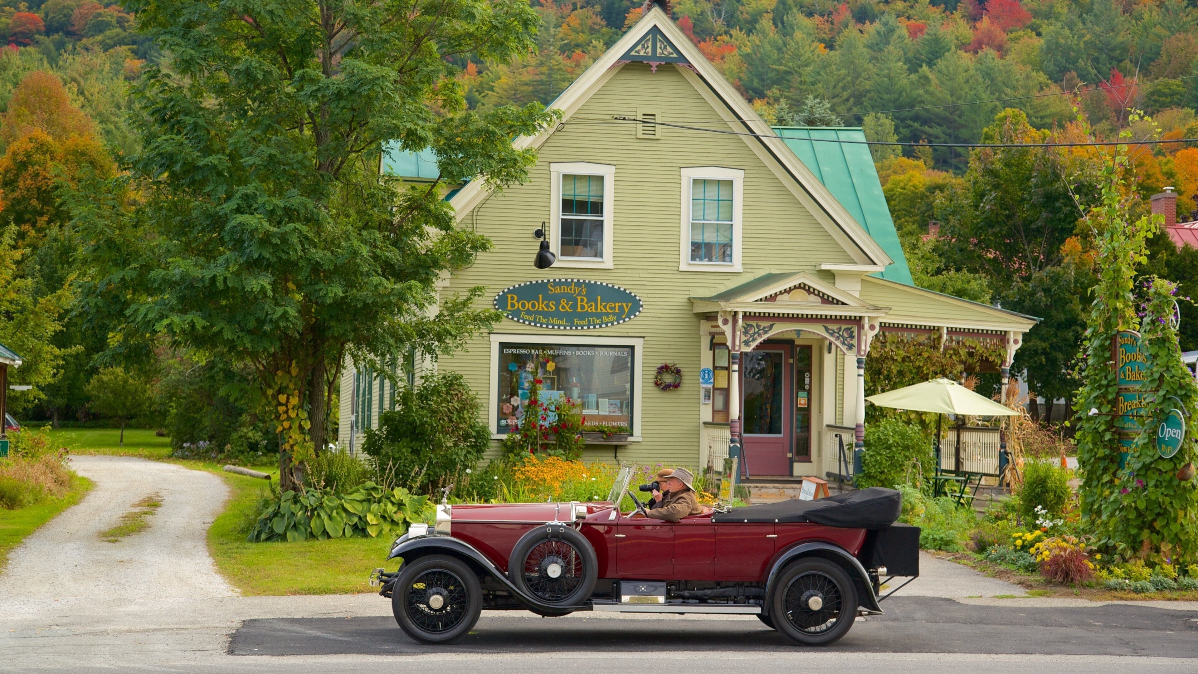 A vintage red convertible parked in front of Sandy's Books & Bakery.