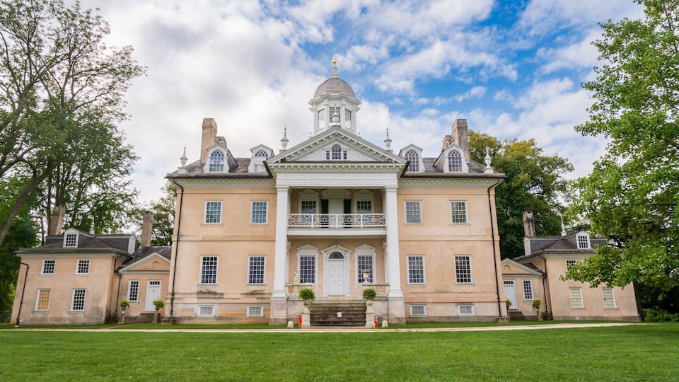 A large stately building with a central dome and symmetrical wings, surrounded by a well-maintained lawn.