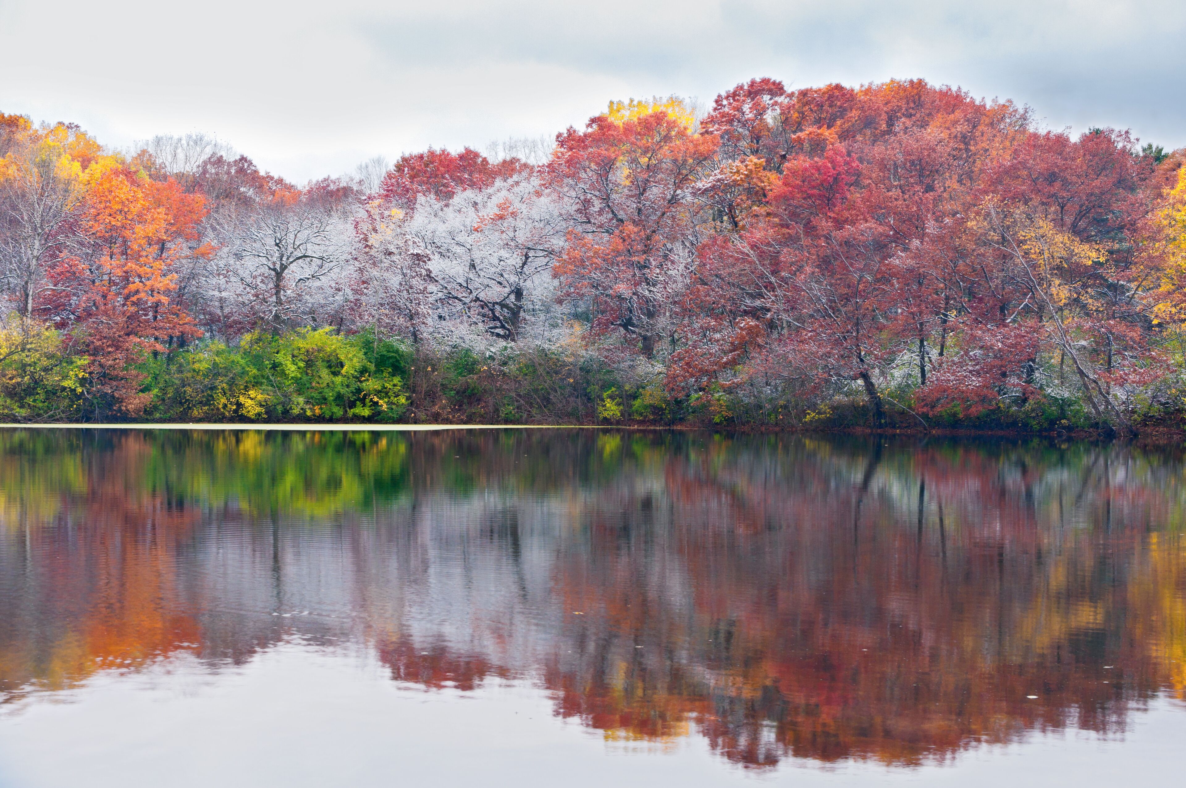 A calm lake reflecting colorful autumn trees.