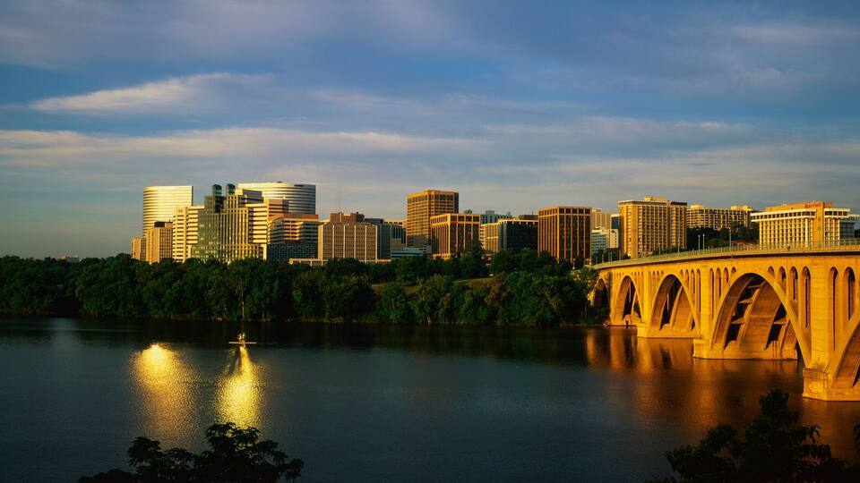 This shows sunrise over the Key Bridge on the Potomac River. The skyline of Rosslyn, Virginia is in the background.