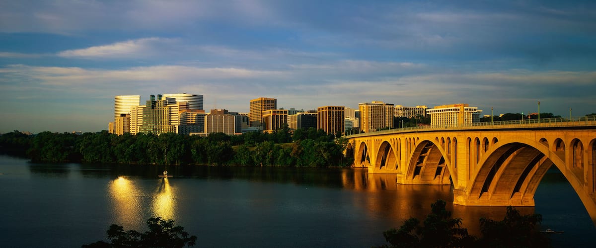 A river with a bridge, a city skyline, and a sunset.