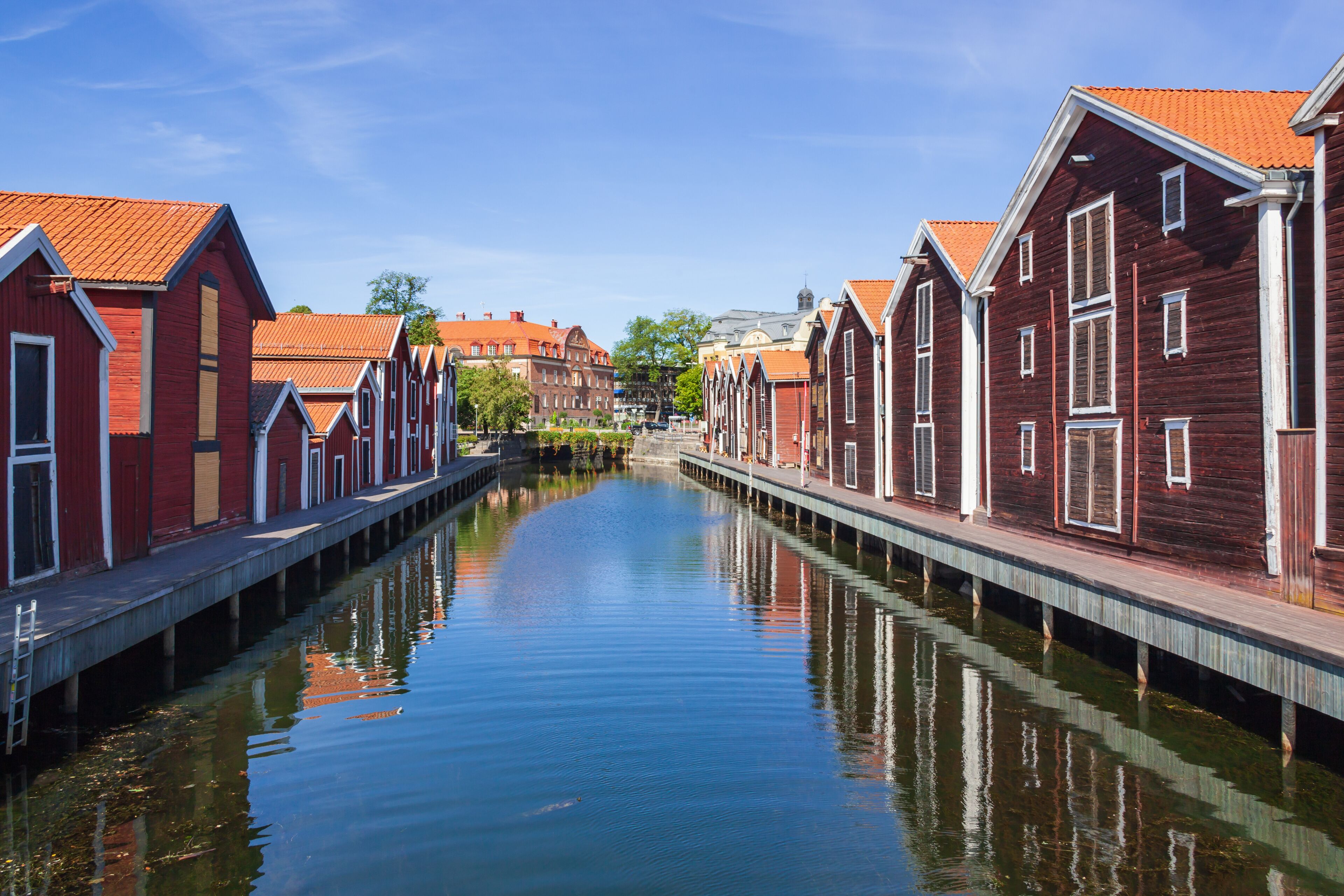 A canal flanked by red wooden houses with white trim and orange roofs.