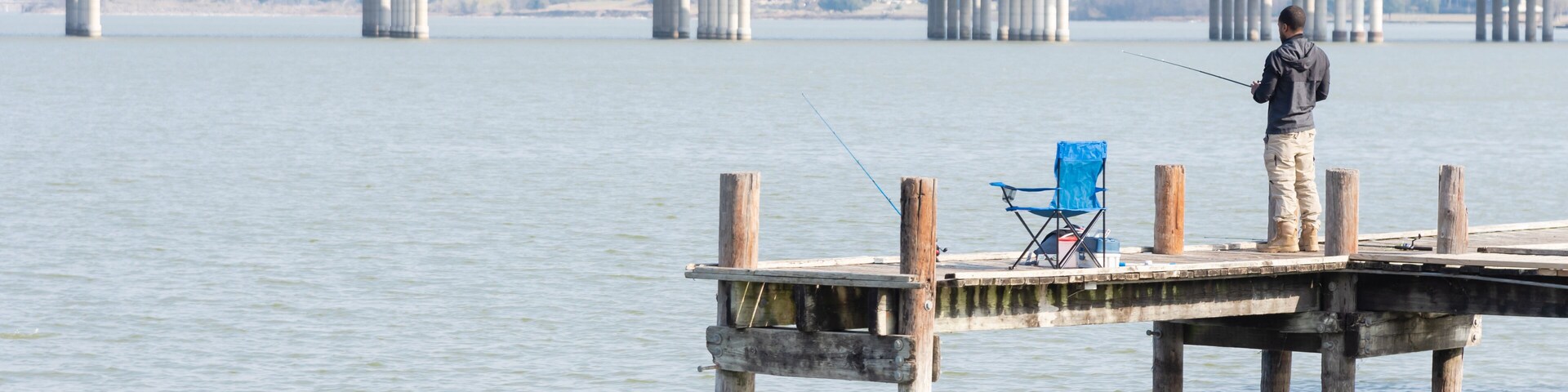 Unidentified fisherman fishing from pier jetty at Lake Ray Hubbard near Dallas, Texas, USA