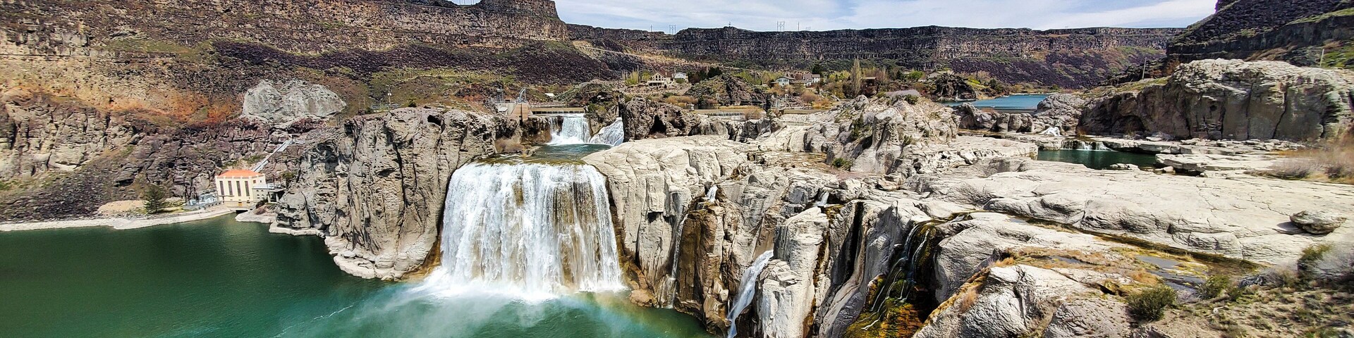 Shoshone Falls Reservoir in Twin Falls, Idaho. Wide angle view of the water flowing over the stone cliffs with a view of the dam and table rocks in the background.