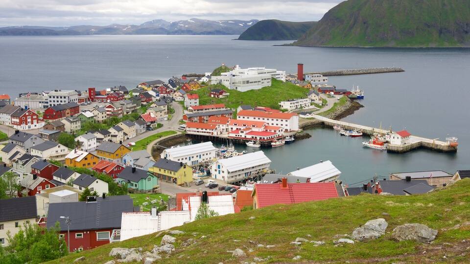 A coastal town with colorful houses, a harbor with boats, and a lighthouse.