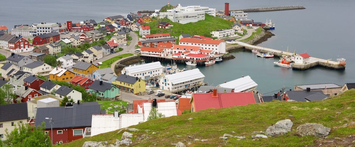 A coastal town with colorful houses, a harbor with boats, and a lighthouse.