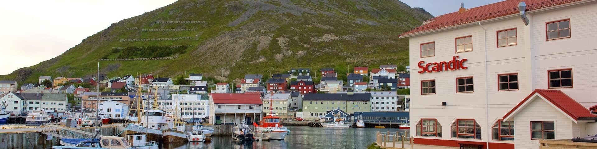 A harbor with boats, a building labeled "Scandic," and a mountain in the background.