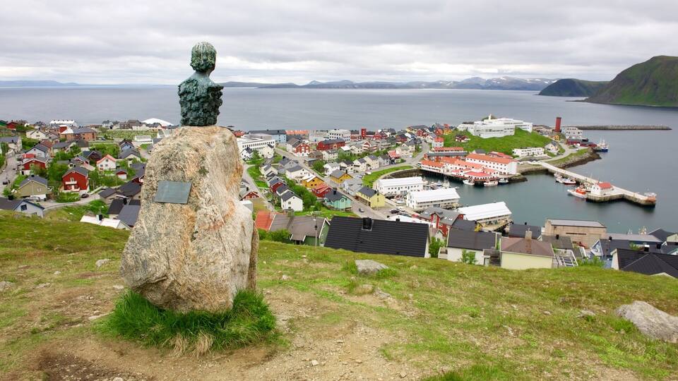 A coastal town with a statue on a hill, houses, and a harbor.