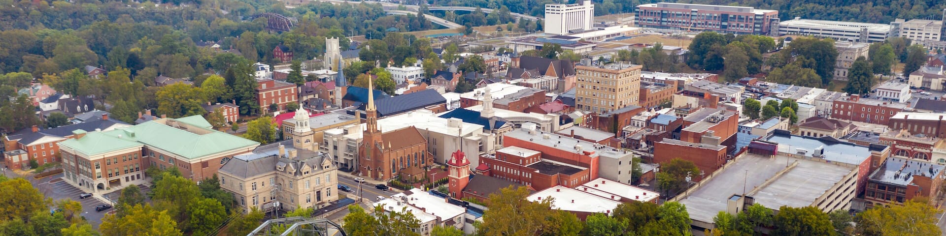 A riverside town with historic buildings, a bridge, and a distant bridge over the river.