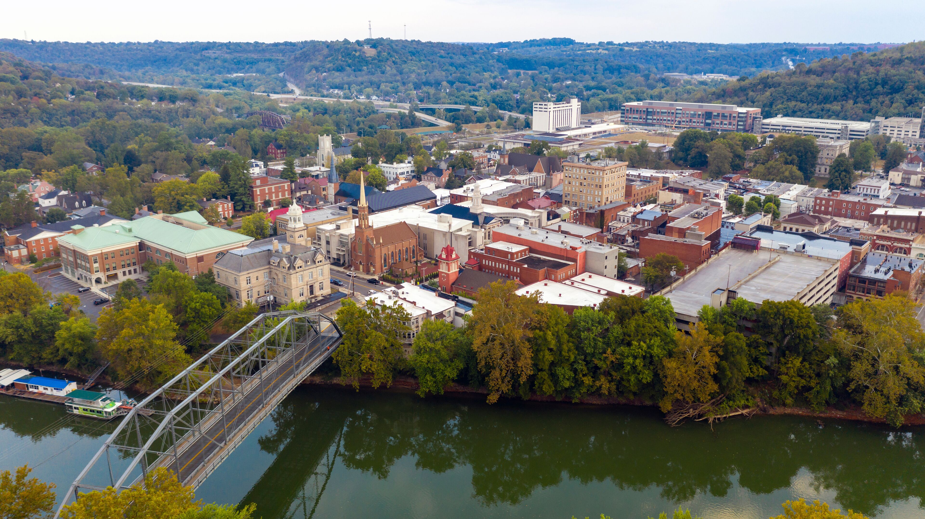 A riverside town with historic buildings, a bridge, and a distant bridge over the river.