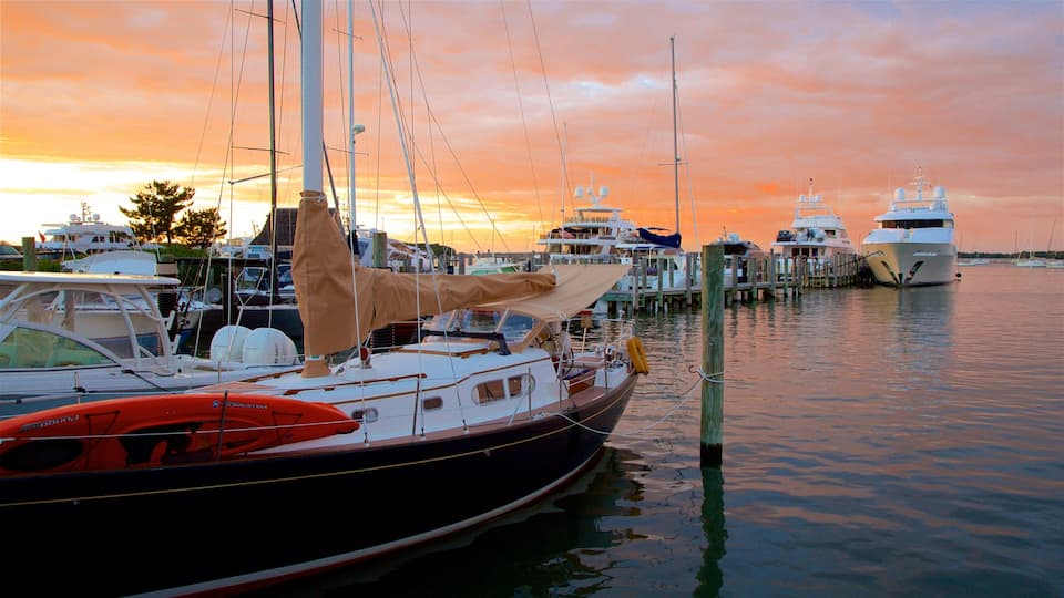 A marina with several boats docked at wooden piers during sunset.