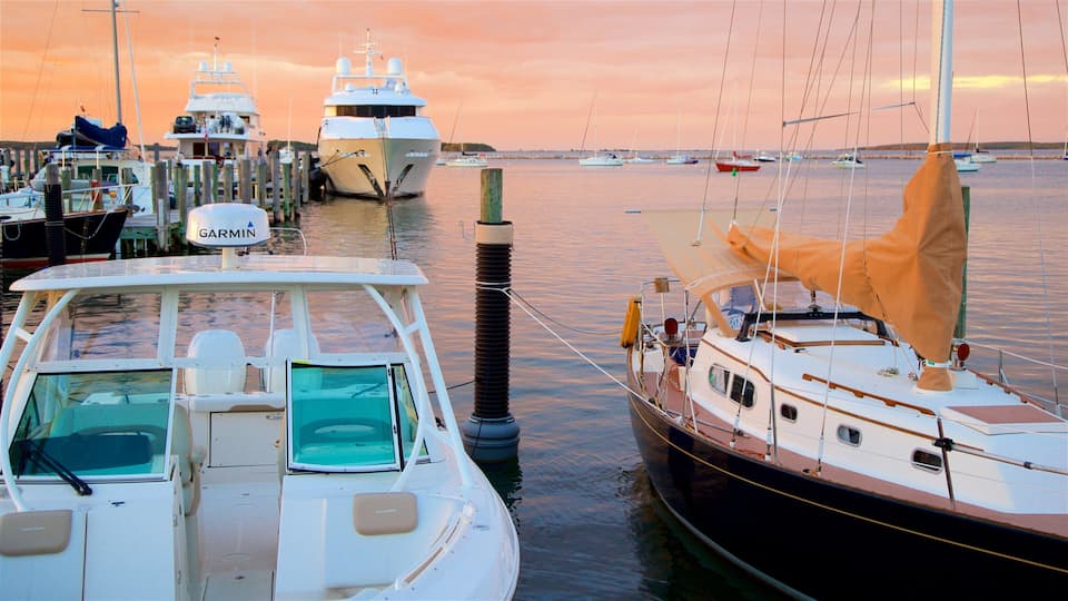 A marina with several boats docked, including a white motorboat and a sailboat with a canopy.