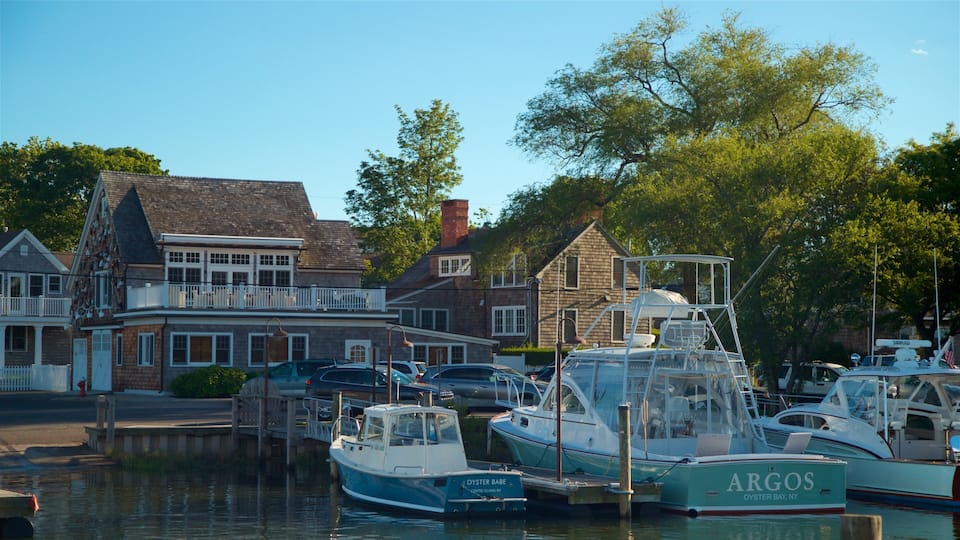A marina with boats docked, a waterfront building, and trees in the background.
