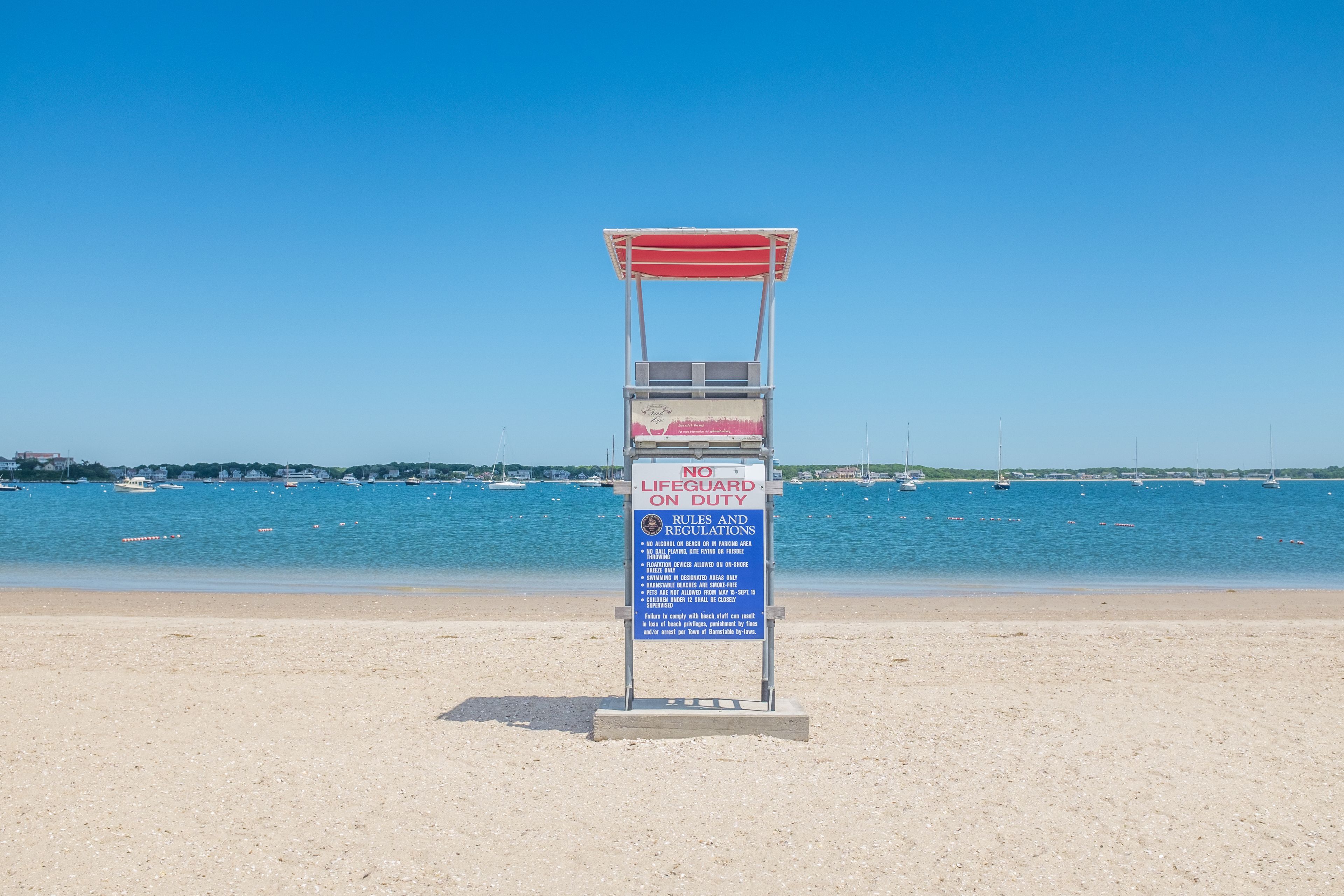 A lifeguard stand on a beach with a clear blue sky and calm sea in the background.