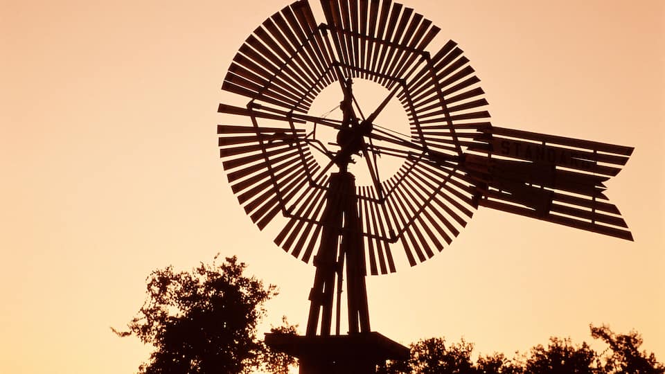 A windmill silhouette against a sunset sky.