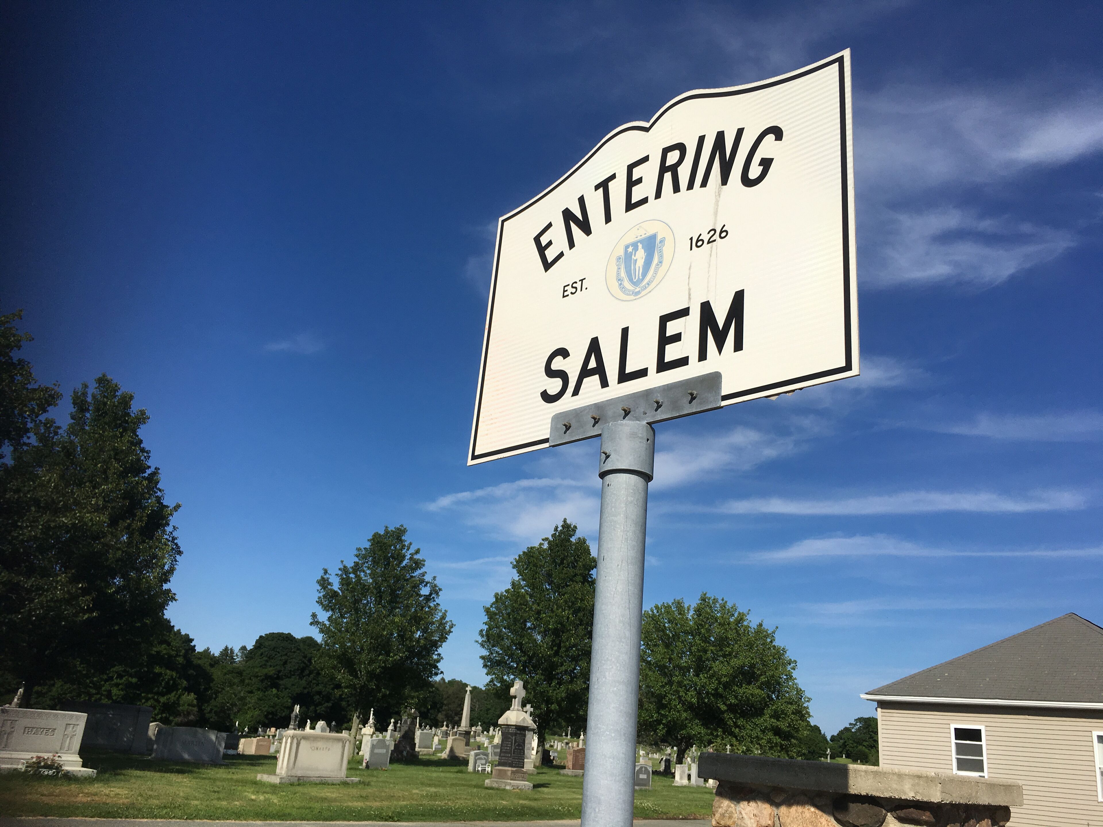A cemetery with headstones and a sign that reads "ENTERING SALEM EST. 1626".