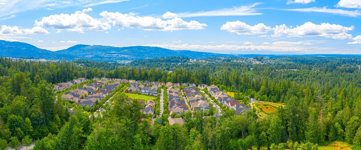 A residential area surrounded by dense forest and mountains.