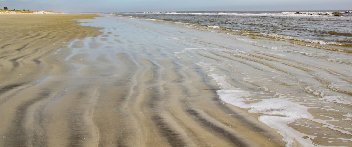 A sandy beach with gentle waves and a clear sky.
