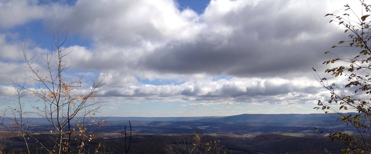 A mountainous landscape with autumn foliage and a cloudy sky.