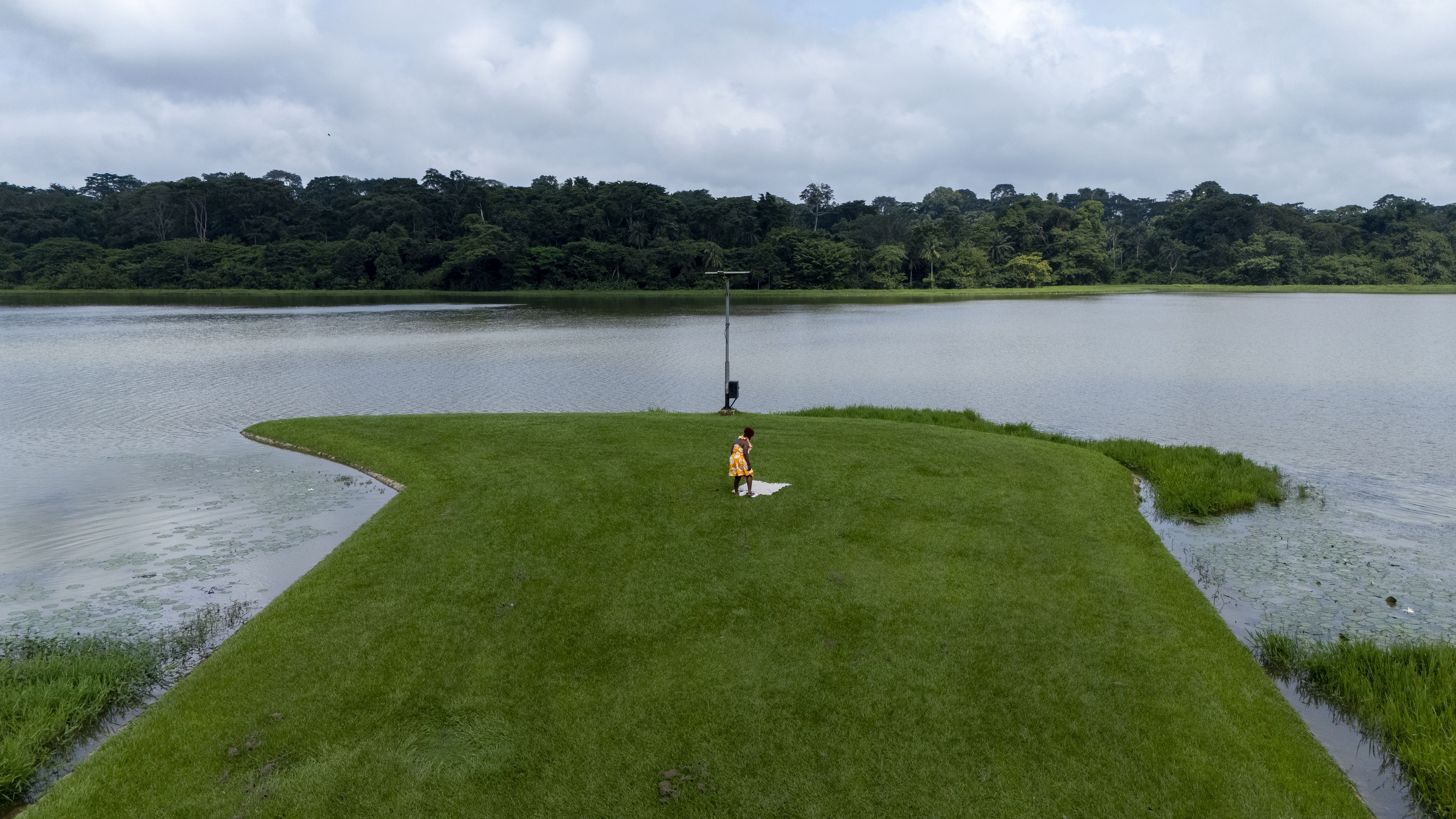 A grassy area with a water body and a person in the center.