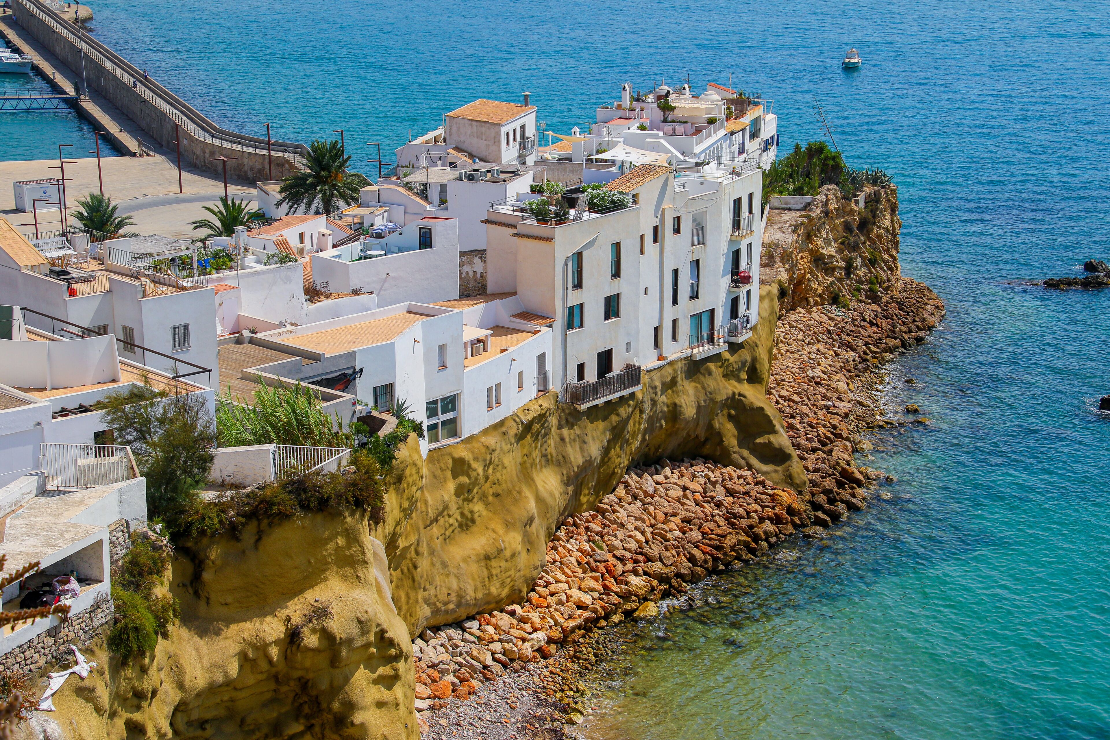 Un pueblo costero con edificios blancos, un litoral rocoso y aguas azul turquesa.