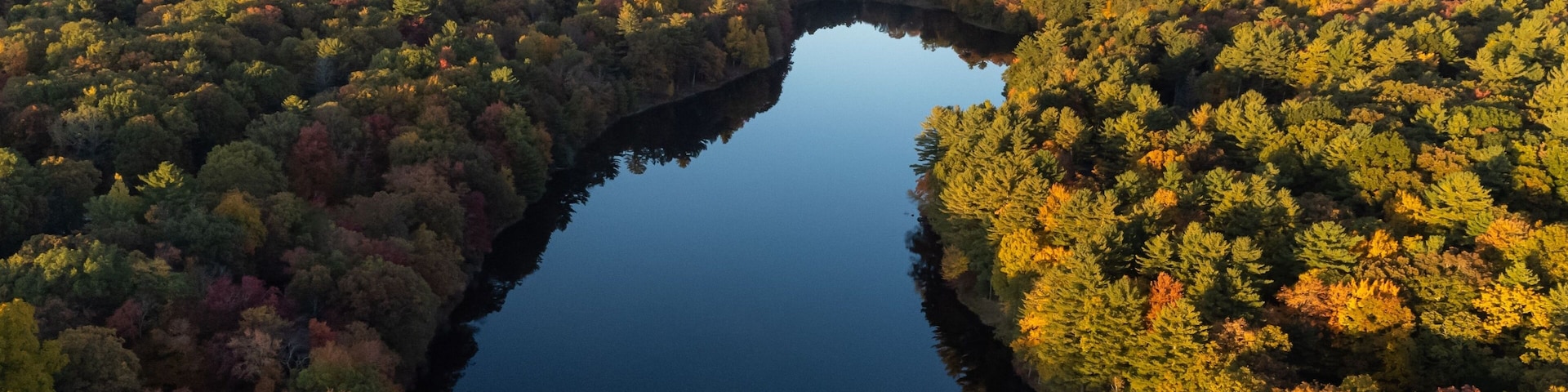 A river winding through a densely forested area with autumn foliage.