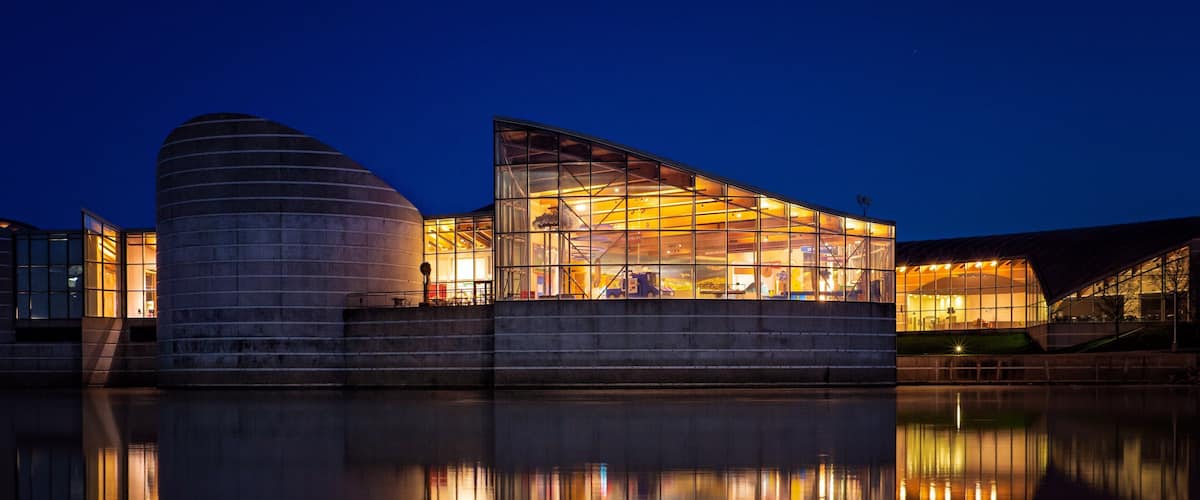 A modern building with a glass facade reflecting in the water.