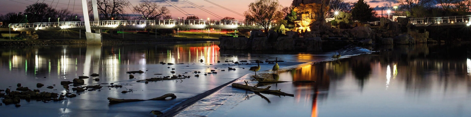 The Keeper of the Plains is a 44-foot tall steel sculpture standing at the point where the Big and Little Arkansas rivers join together in downtown Wichita. This land between the two rivers is sacred ground to the Native American people and is also home to the Mid-America All-Indian Center. The Indian Warrior sculpture was created by Wichitan and Native American artist Blackbear Bosin (1921-1980).
Come in time for the sunsets to enjoy the view along the eastern shore of the Arkansas River. 
#Wichita #Kansas #Sunset #Reflections