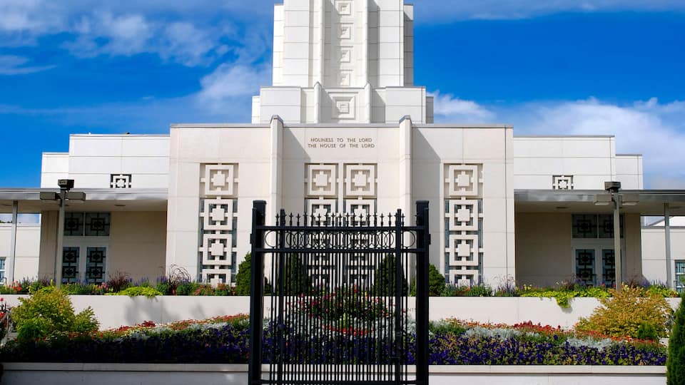 A white building with a tall spire and a golden statue on top.