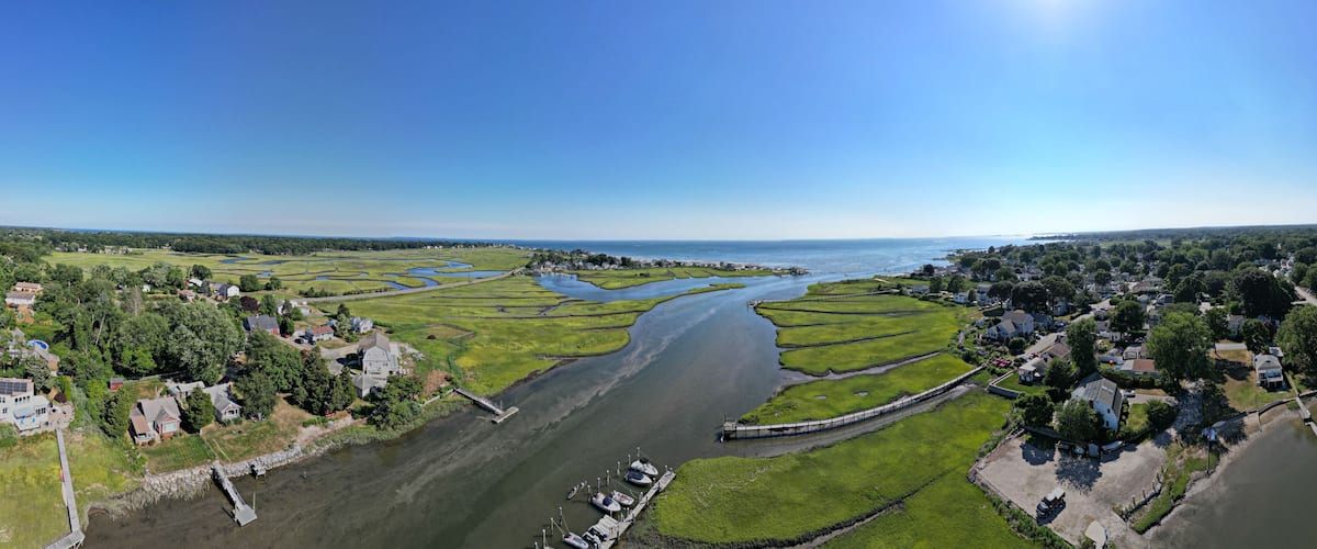 A river meandering through a rural landscape with fields, a bridge, and houses along the banks.