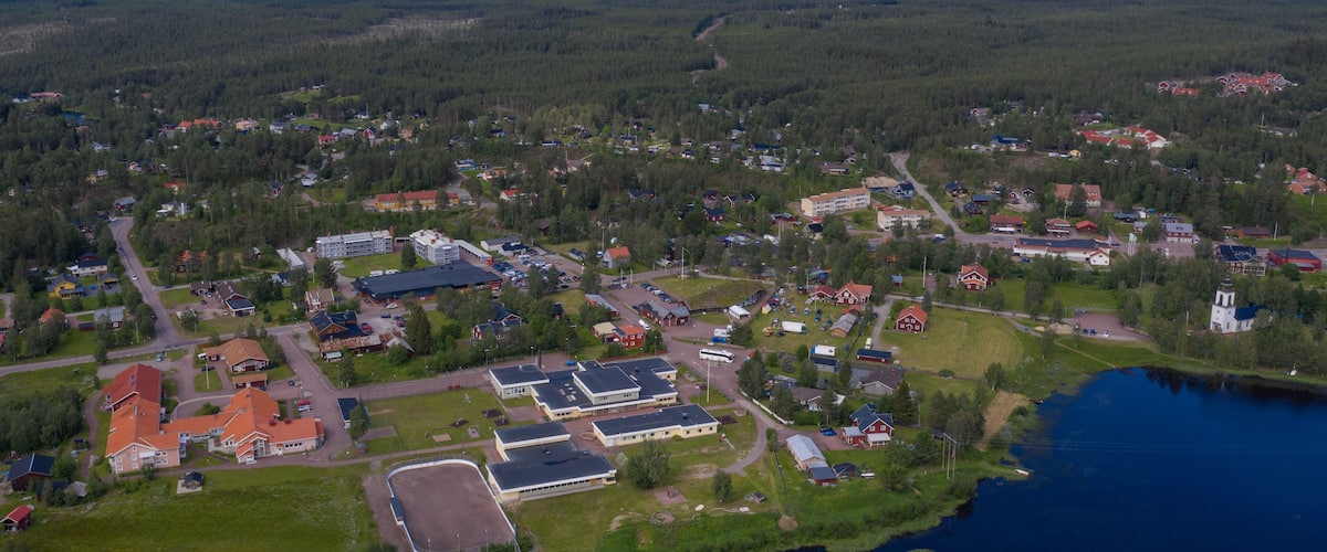 A lakeside community with residential buildings, a large parking lot, and a mountain in the background.