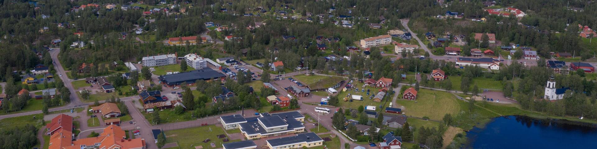 A lakeside community with residential buildings, a large parking lot, and a mountain in the background.